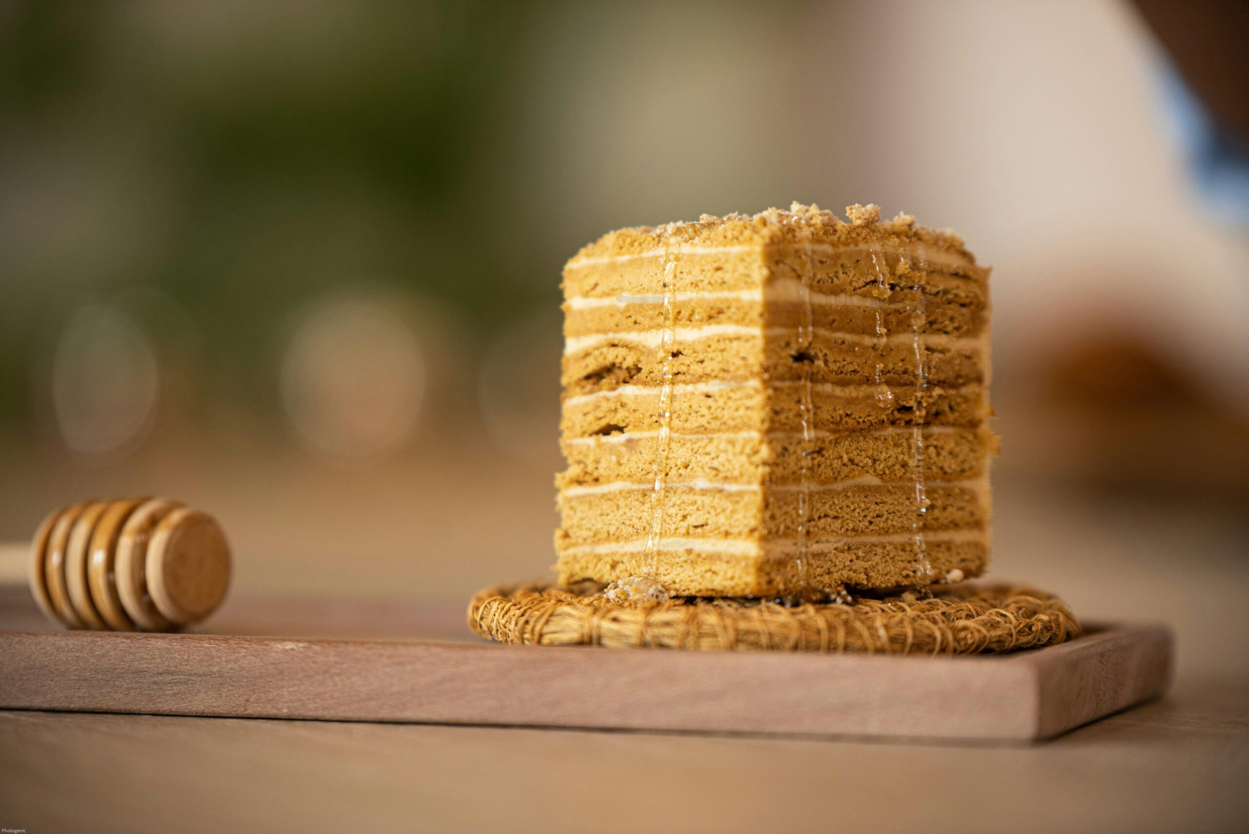 Delicious slice of layered Medovik honey cake on a rustic wooden board with honey drizzle.