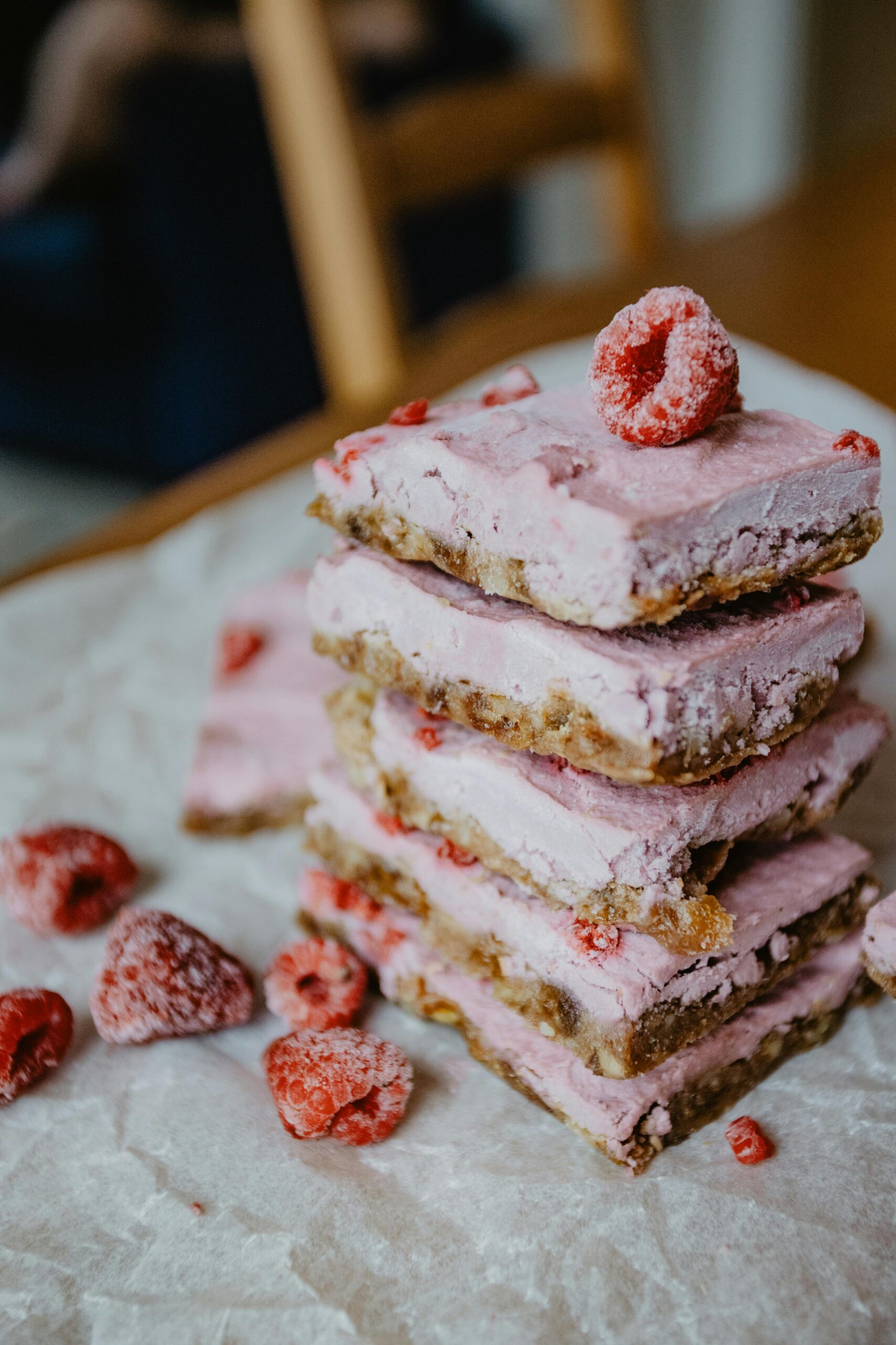 Close-up of raspberry dessert bars stacked with fresh raspberries for food photography.