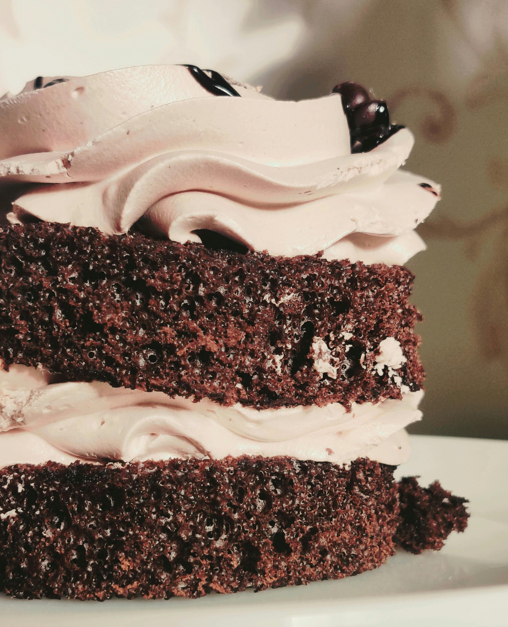 Close-up of a rich chocolate cake with swirls of whipped icing, showcasing dessert indulgence.